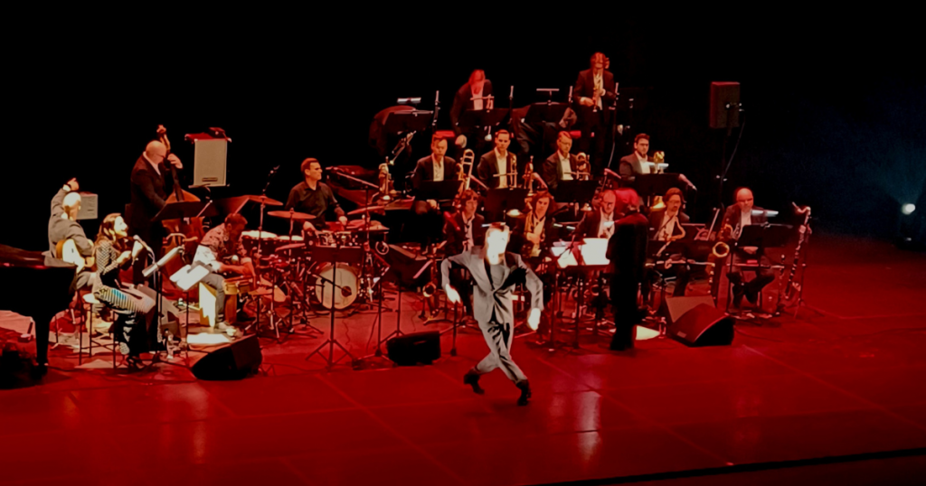 kuva UMO jazz flamenco -konsertista, iso ryhmä soittajia punasävyisesti valaistulla lavalla
